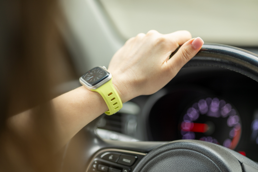 Жіноча рука на кермі авто з Apple Watch у яскравому салатовому ремінці Nomad Tempo Lumen